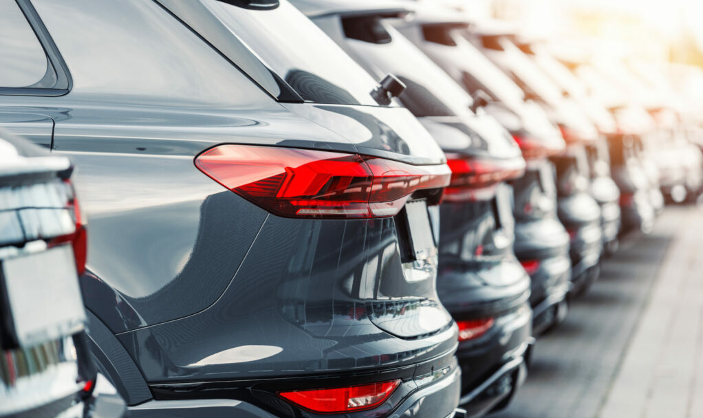 Back view many modern new SUV cars fleet stock at dealership parking lot. Automobile market production factory industry warehouse. Auto salvage buy and sell auction purchase seller platform